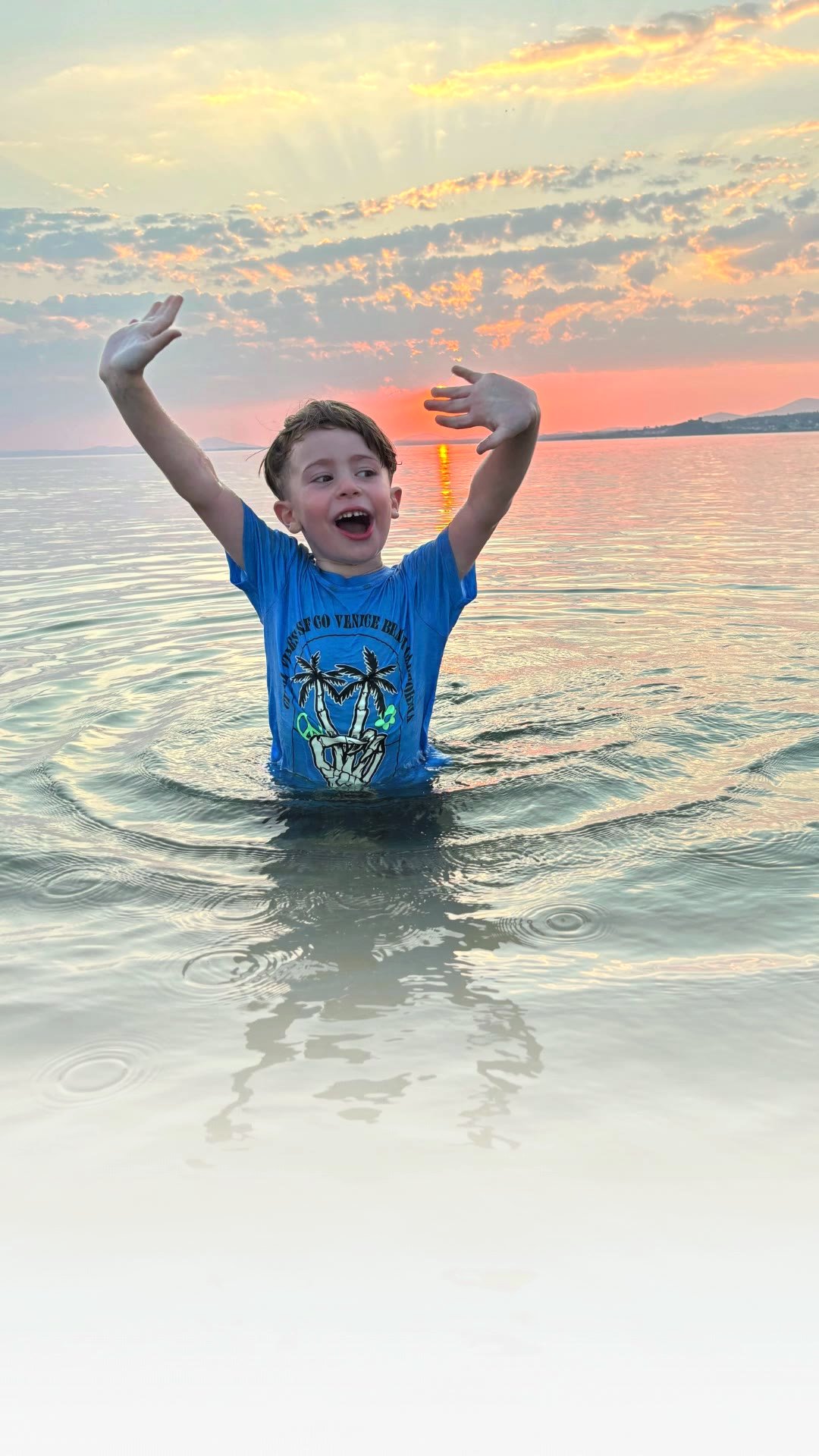 A boy waving in the sea at sunset on holiday at Giddo’s Gaff